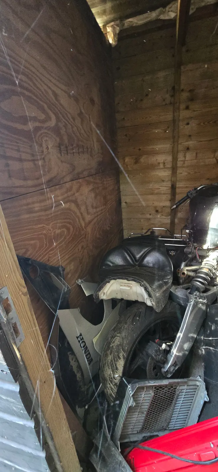A motorcycle stored tightly inside a timber shed
