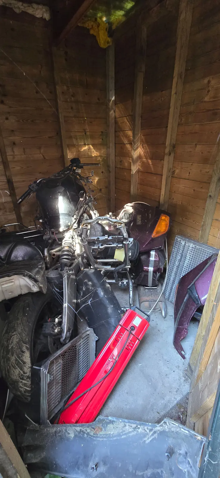 A second view of a stored donor motorcycle in the shed